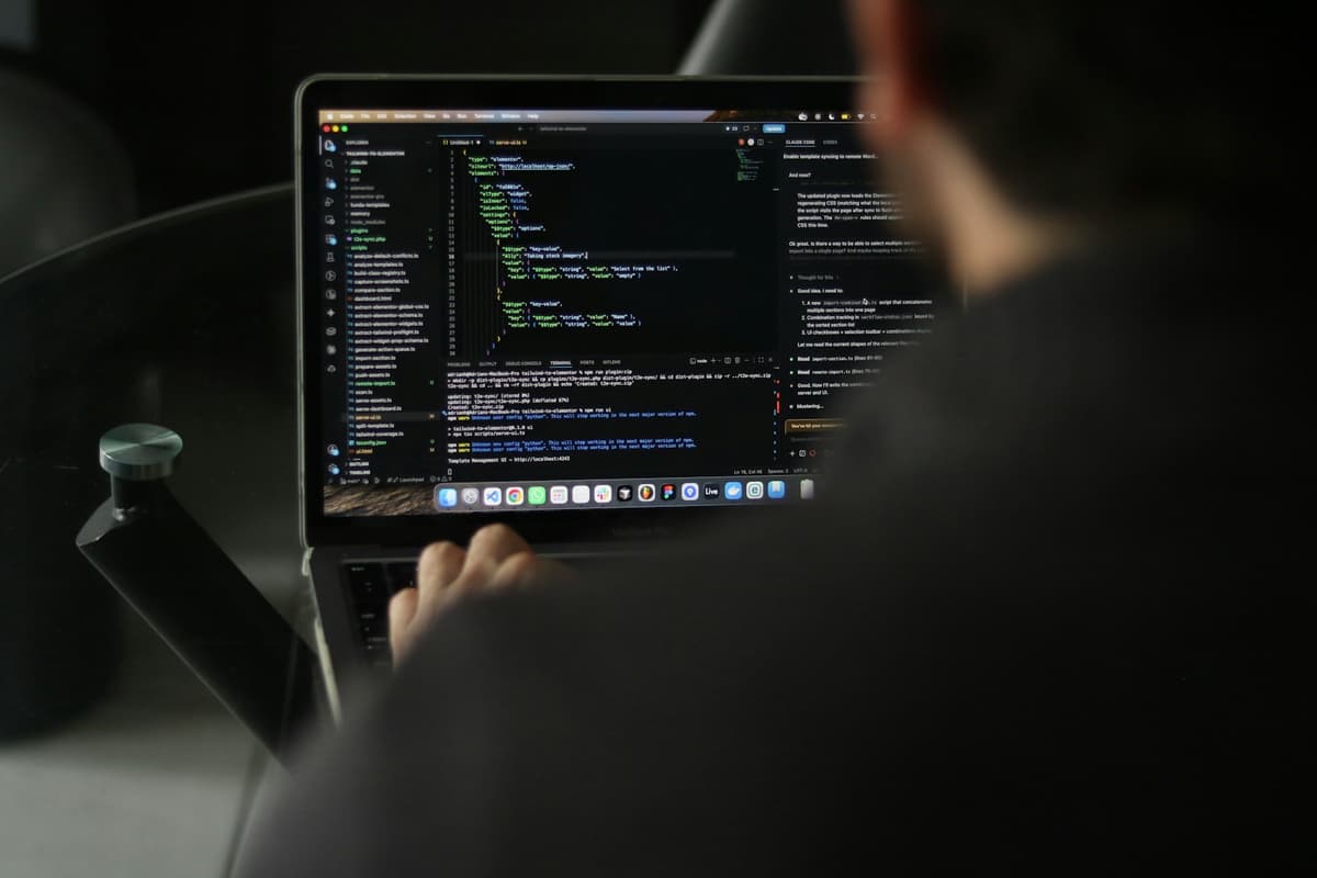 Laptop showing software code on a screen beside a smartphone, representing custom application development